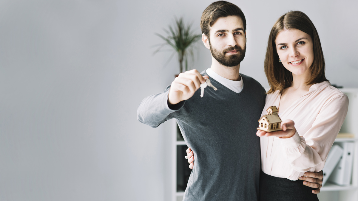 A couple holding a model house and keys